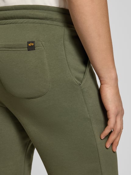 Männermodel trägt Shorts mit Eingrifftaschen und Logo-Print von Alpha Industries in Olivgrün, Baumwoll-Mix mit Gesäßtasche, Detailaufnahme Rückansicht.