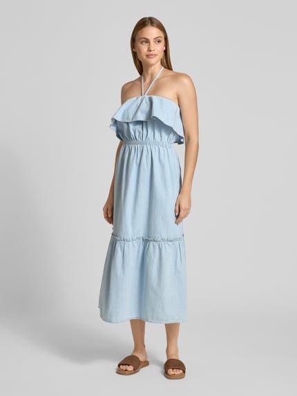 Frauenmodel trägt Jeanskleid mit Neckholder Modell 'LUMIRA' von Drykorn aus Reiner Baumwolle, Taillierter Schnitt, Midikleid, hellblau, Volant am Ausschnitt, Ganzkörperansicht von vorne.