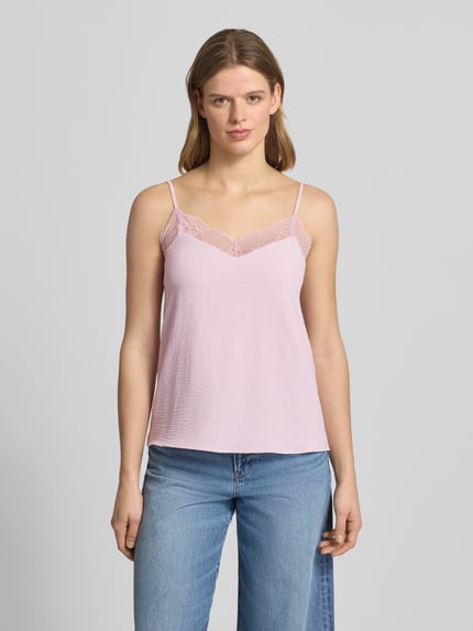 Kobiece model nosi Relaxed Fit Blusentop mit Spitzenbesatz Modell 'TIFFANY' von Pieces, efekt: jednolity kolor, dekolt w serek, obszycie koronką, cienkie regulowane ramiączka, wykończenie materiału: krepa; jasnoróżowy, struktura lekko falista, delikatne koronki, Ganzkörperansicht von vorne.
