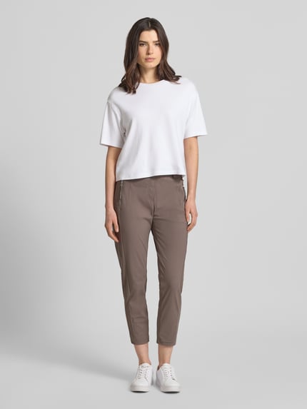 Frauenmodel trägt Stoffhose in 7/8-Länge mit Stretch-Anteil Modell 'NATINA' von Raffaello Rossi, Elastischer-Material-Mix, körpernahe Passform, Elastikbund mit Gürtelschlaufen, Reißverschlusstaschen, Bundweite 40 cm, Innenbeinlänge 69 cm, Ganzkörperansicht von vorne.