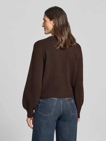 Frauenmodel trägt Strickjacke mit Zierknöpfen Modell 'VMHAZEL' von VERO MODA, braune Melange-Optik, Ballonärmel, Ganzkörperansicht Rückansicht.