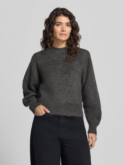 Frauenmodel trägt Pullover aus Mohair mit überschnittenen Schultern von Selected, dunkles Grau, weiche Textur, Ganzkörperansicht von vorne.
