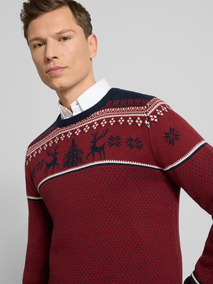 Männermodel trägt Strickpullover mit gerippten Abschlüssen van Lindbergh in rood met donkerblauw, katoenmix, regular fit, ronde hals, ruglengte maat M 72 cm, mouwlengte 78 cm, nahaufnahme bovenlichaam.