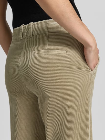 Kobiece model prezentuje spodnie sztruksowe 'Flared Fit Cordhose aus Baumwoll-Mix' od Marc O'Polo, beżowy kolor, wyrazista struktura prążków, detal tylnej części, zbliżenie na biodra, moda damska
