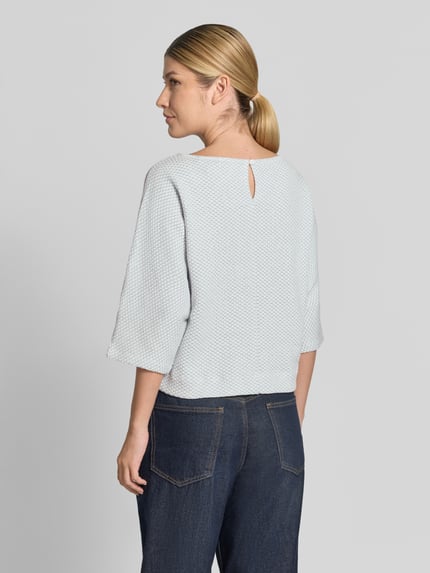 Frauenmodel trägt Loose Fit Pullover mit Baumwoll-Anteil Modell 'Sassoni' von OPUS, helles Strickmuster, strukturierte Oberfläche, Ganzkörperansicht Rückansicht. Damen Pullover von OPUS.