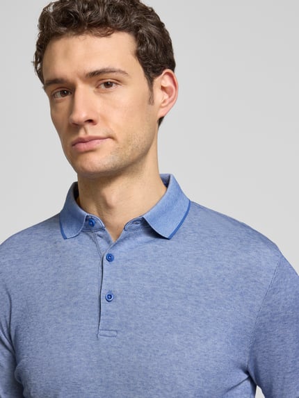 Männermodel trägt Slim Fit Poloshirt mit Label-Detail von HECHTER PARIS, blaue Baumwollmischung, glatte Textur, Nahaufnahme Oberkörper.