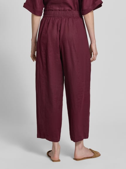 Vrouwenmodel draagt Leinenhose in verkürzter Passform mit elastischem Bund van Christian Berg Woman, zuiver linnen, wide leg, tunnelkoord, verkort, binnenbeenlengte maat 36: 64 cm, bandwijdte maat 36: 38 cm, ganzkörperaanzicht achterkant.