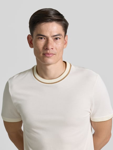 Männermodel trägt Regular Fit T-Shirt aus reiner Baumwolle Modell 'H-THOMPSON 81' von BOSS, cremefarben mit Kontrastbündchen, Nahaufnahme Oberkörper, Herren T-Shirt.