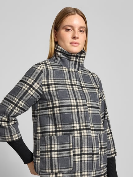 Frauenmodel trägt Kurzmantel mit Stehkragen Modell 'SC-GERLINDE 2' von SOYACONCEPT, kariertes Allover-Muster, Nahaufnahme Oberkörper.