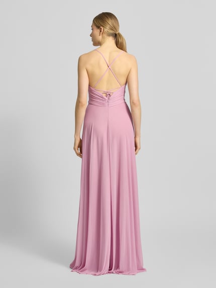 Modelka nosi sukienka wieczorowa 'Abendkleid mit rückseitig überkreuzten Spaghettiträgern' od Jake*s Cocktail, szyfon, linia a, długa sukienka, dekolt w serek, marszczenia, cienkie ramiączka krzyżowane z tyłu, wiązanie z tyłu, zapięcie na haftkę i zamek błyskawiczny; długość tyłu w rozmiarze 36: 126 cm, szerokość w rozmiarze 36: 38 cm, różowy kolor, lekko błyszcząca tekstura, widok całej sylwetki z tyłu.