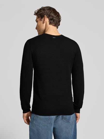 Męski model nosi Regular Fit Strickpullover aus Viskose-Mix od Antony Morato, czarny, strukturalna faktura, krój regular fit, okrągły dekolt, elastyczne wykończenia, długość tyłu 67 cm, długość rękawa 65 cm, całkowity widok z tyłu.