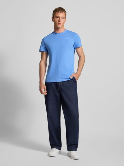 Männermodel trägt Slim Fit T-Shirt aus reiner Baumwolle von Tommy Jeans, Optik: Unifarben, Label-Print, Rundhals, Kurzarm, Ganzkörperansicht von vorne.