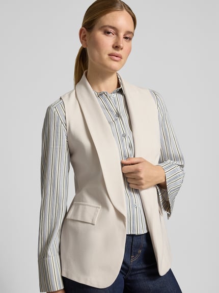 Kobiece model nosi kamizelkę z mieszanki wiskozy z dodatkiem streczu ZABAIONE, krój straight fit, szalowy kołnierz, kieszenie z patką, model 'Am44br', długość tyłu w rozmiarze S: 70 cm, szerokość ramion w rozmiarze S: 33 cm, szerokość w klatce piersiowej w rozmiarze S: 48 cm, widok na górną część ciała z przodu