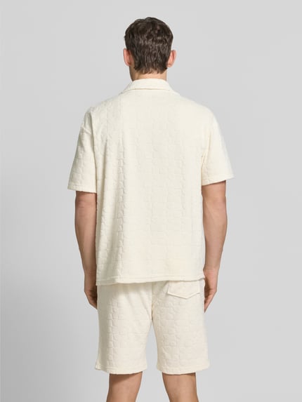 Männermodel trägt Regular Fit Freizeithemd mit Strukturmuster von MCNEAL in Creme, sichtbare Knopfleiste und Reverskragen, Ganzkörperansicht Rückansicht. Baumwoll-Mix, lockerer Schnitt, kurze Ärmel, strukturierte Oberfläche, Rückenlänge 74 cm, Schulterbreite 40 cm, Ärmellänge 25 cm.
