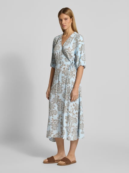 Modelka kobieca nosi Midikleid aus Viskose in Wickel-Optik mit 1/2-Arm od JAKE*S STUDIO WOMAN, jasnoniebieskie w beżowy wzór, czysta wiskoza, krój taliowany, dekolt w serek, długość tyłu w rozmiarze 36: 124 cm, szerokość w rozmiarze 36: 55 cm, długość rękawa w rozmiarze 36: 41 cm, widok całej sylwetki z przodu.