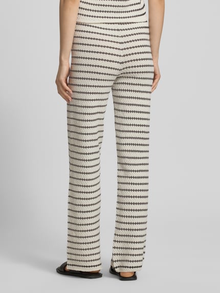 Frauenmodel trägt Strickhose in Streifen-Optik mit elastischem Bund von REVIEW, Material-Mix mit Baumwoll-Anteil, Flared Cut, Ganzkörperansicht Rückansicht.