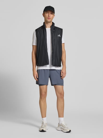 Männermodel trägt Regular Fit Trainingsjacke mit Belüftungsschlitz am Rücken von adidas Training in Schwarz, Ganzkörperansicht von vorne.