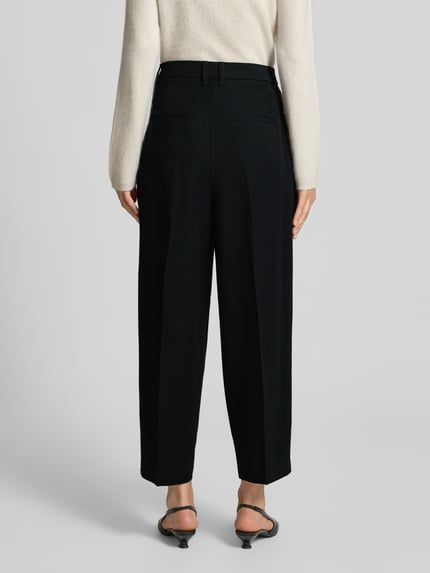 Frauenmodel trägt Barrel Fit Hose mit Viskose-Anteil von s.Oliver RED LABEL in Schwarz, gerade Form, glatte Textur, Ganzkörperansicht Rückansicht, Damen Barrel Jeans von s.Oliver RED LABEL.