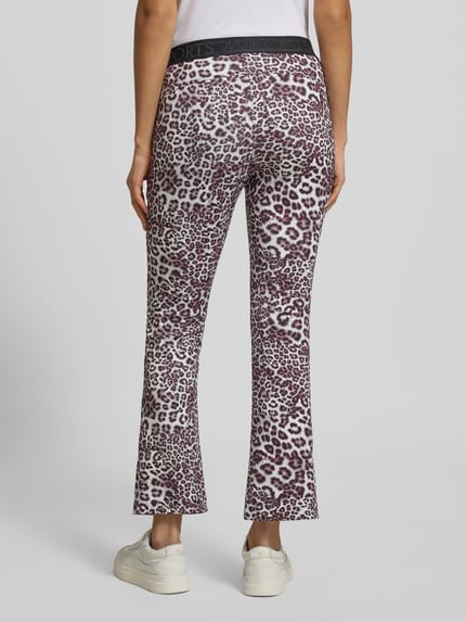 Vrouwenmodel draagt Flared Fit Stoffhose mit Allover-Animal-Print van Marc Cain, elastische stof, flared pasvorm, elastische tailleband, damesbroek met dierenprint, productinformatie voor maat 36, volledige lichaamsweergave achteraan.