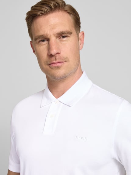 Männermodel trägt Regular Fit Poloshirt aus reiner Baumwolle Modell 'INTERLOCK' von BOSS Orange, weiß, unifarben, Nahaufnahme Oberkörper.