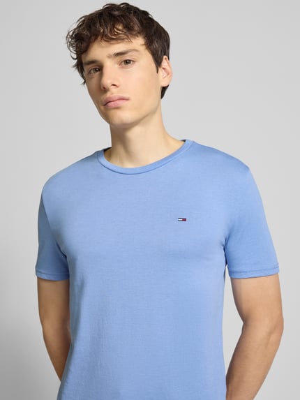 Männermodel trägt Regular Fit T-Shirt aus Baumwoll-Mix von Tommy Jeans, Optik: Unifarben, Logo-Stitching, Nahaufnahme Oberkörper.