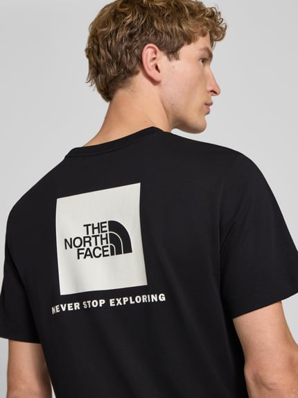 Mannenmodel draagt t-shirt met labelprint Model 'Evolution' van The North Face, katoenmix, regular fit, ruglengte maat M 73 cm, detailopname rugaanzicht.