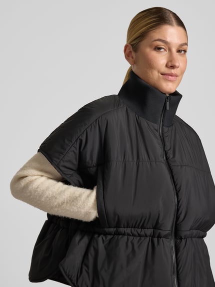 Frauenmodel trägt schwarze Steppweste mit Stehkragen Modell 'Vanjah' von someday, entspannte Form, Nahaufnahme Oberkörper.