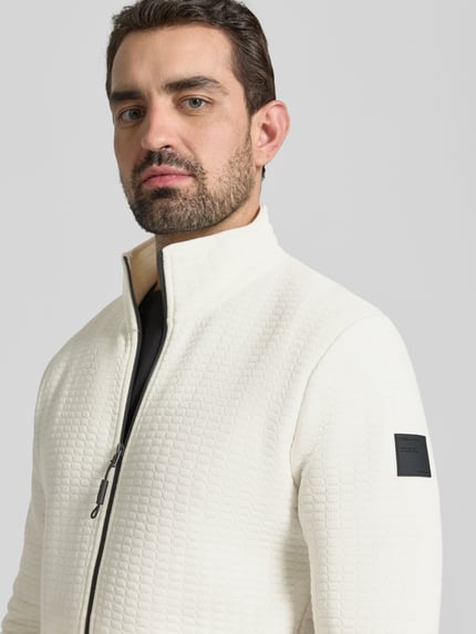 Mannelijk model draagt Loose Fit Sweatjacke aus Baumwoll-Mix van Tom Tailor Denim in effen wit met label patch, opstaande kraag, sweat crinkle textuur, lange mouwen, zijzakken, katoenmengsel; detailopname bovenlichaam.