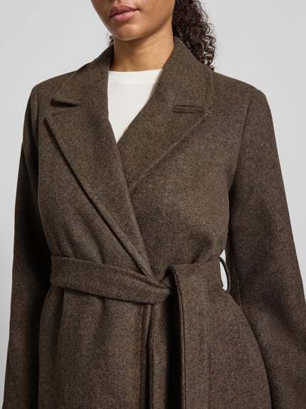 Kobiece modelka nosi Mantel mit Bindegürtel od ONLY, płaszcz krótki, jednolity kolor, fason kopertowy, kołnierz z klapami, długie rękawy, pasek do wiązania w talii, zbliżenie na górną część ciała.