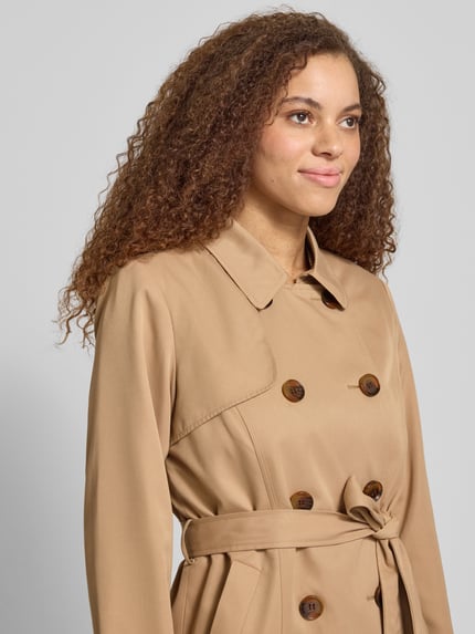 Frauenmodel trägt Regular Fit Trenchcoat mit doppelreihiger Knopfleiste Modell 'VALERIE' von ONLY, Optik: Unifarben, Umlegekragen, Taillengürtel, langarm, seitliche Eingrifftaschen, Nahaufnahme Oberkörper.