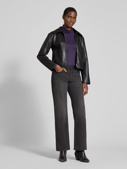 Frauenmodel trägt Slim Fit Longsleeve aus elastischem Viskose-Mix Modell 'Liana' von FREE/QUENT in Lila, kombiniert mit schwarzer Jacke und Jeans, Ganzkörperansicht von vorne. Damen Longsleeve, elastischer Viskose-Mix, Rollkragen, Rückenlänge bei Größe S: 53 cm.