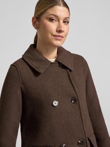 Frauenmodel trägt Mantel mit Webpelzkragen von VERO MODA in Braun, unifarben, strukturierte Oberfläche, Zierknöpfe, Nahaufnahme Oberkörper.