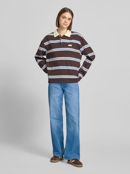 Vrouwenmodel draagt Wide Leg Jeans aus Baumwoll-Mix Modell 'JUDY' van Only in uni denimlook met low waist, label stitching, 5-pocket, knoopsluiting, riemlussen, materiaal katoenmix, volledig frontaal zicht.