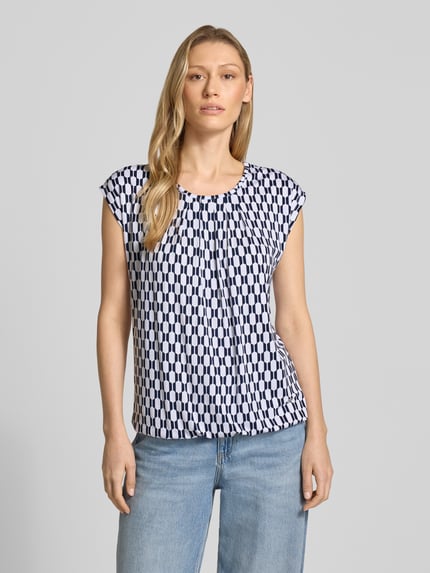 Modelka nosi Blusenshirt mit Rundhalsausschnitt von ZABAIONE, biało-granatowy wzór, prosty krój, krótki rękaw, mieszanka wiskozy i elastanu, długość pleców w rozmiarze S 58 cm, widok całej sylwetki z przodu.