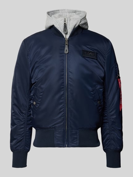 Produktfoto, Bomberjacke mit Kapuze und Label-Details von Alpha Industries, dunkelblau mit Reißverschluss, Eingrifftaschen, strukturierte Bündchen, Regular Fit, Kapuze in Grau, detailreiche Textur und sichtbare Label-Elemente, Herrenmodell gemäß Größenangaben.