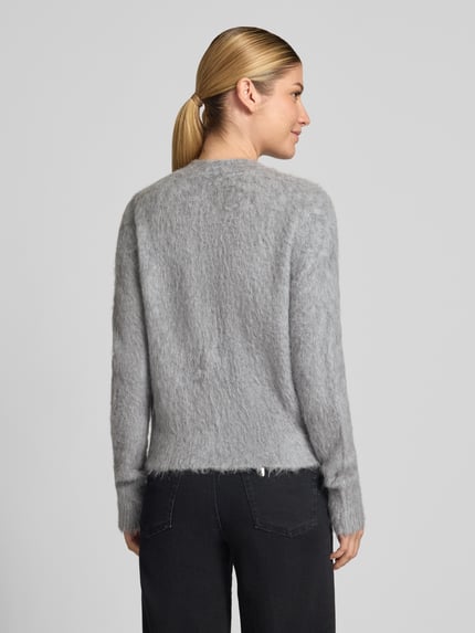 Frauenmodel trägt Strickjacke aus Alpaka-Mix Modell 'Tulinda' von someday., graue Farbe, weiche Textur, Ganzkörperansicht Rückansicht. Damen Strickjacke, Regular Fit, Rundhalsausschnitt, Knopfleiste, Rückenlänge 53 cm, Ärmellänge 80 cm.