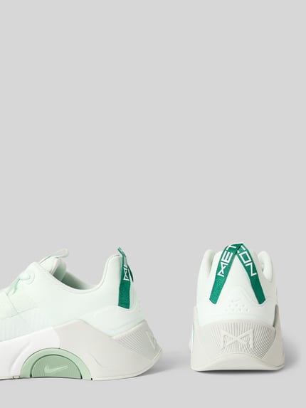 Productfoto, Sneaker met logo-detail model 'Metcon' van Nike, afgeronde pasvorm, vetersluiting, witte en lichtgroene kleuren, hakhoogte 6 cm, schachthoogte 7 cm, schachtwijdte 6 cm, dames sneaker, textuur van mesh en rubber.