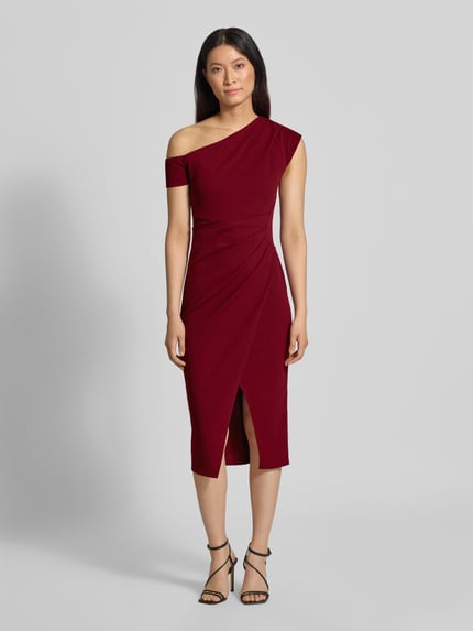 Frauenmodel trägt Knielanges Kleid mit Gehschlitz von Lipsy in Weinrot, Slim Fit, asymmetrisch, Off-Shoulder, elastischer Material-Mix, Ganzkörperansicht von vorne.