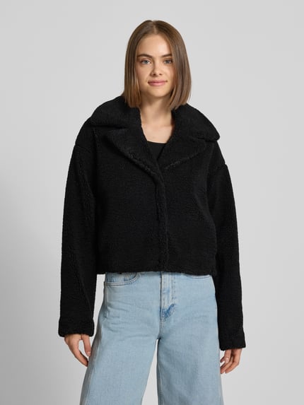 Vrouwenmodel draagt Cropped Jacke aus Teddyfell Modell 'Nati' van NOISY MAY®, zwart teddy, cropped fit, reverskraag, Ganzkörperaanzicht van voren.