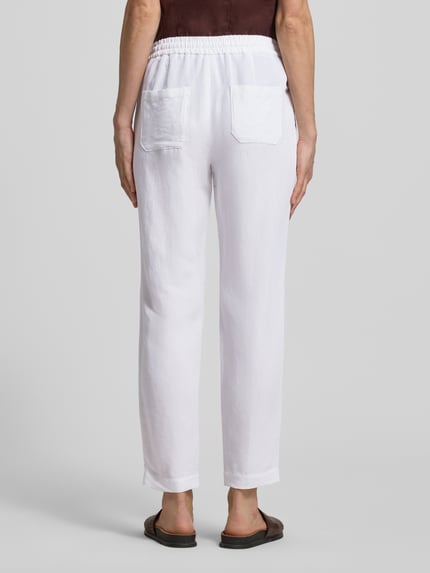 Vrouwenmodel draagt Straight Fit Stoffhose aus Viskose-Mix mit Leinen-Anteil van Marc Cain in wit, elastische tailleband met tunnelkoord, steekzakken, linnen-look textuur, maat 36: taillewijdte 37 cm, binnenbeenlengte 66 cm. Volledige lichaamsopname achteraanzicht.