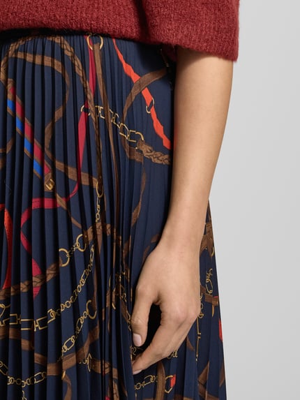 Frauenmodel trägt Midirock mit Plisseefalten von Lauren Ralph Lauren, A-Linie, blau mit buntem Kettenmuster, Nahaufnahme Oberkörper.