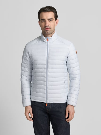 Männermodel trägt hellblaue Steppjacke mit Zweiwegereißverschluss Modell 'Alexander' von SAVE THE DUCK, Regular Fit, Ganzkörperansicht von vorne.