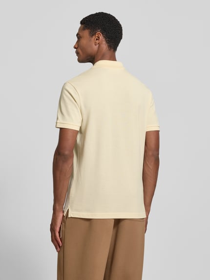 Męski model nosi Slim Fit Poloshirt aus reiner Baumwolle von Lacoste, kremowa koszulka, gładka faktura, całkowity widok z tyłu.