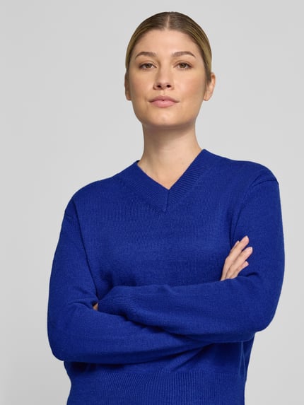 Frauenmodel trägt Strickpullover mit V-Ausschnitt Modell 'LIMONI' von MANGO in Blau, elastische Abschlüsse, Nahaufnahme Oberkörper.