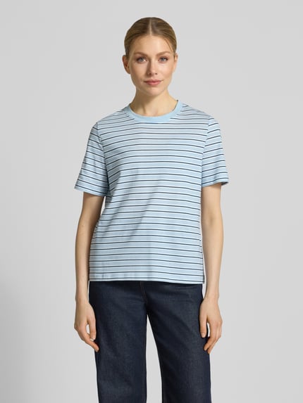 Kobiece modelka nosi damski t-shirt Regular Fit T-Shirt aus reiner Baumwolle Modell 'PAULINA' von Vero Moda, efekt: wzór w paski, okrągły dekolt, krótki rękaw, dżersej z czystej bawełny, jasnoniebieski z cienkimi ciemniejszymi paskami, faktura miękka, Ganzkörperansicht von vorne.