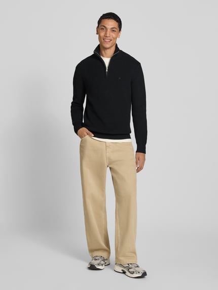 Męski model nosi Slim Fit Pullover aus reiner Baumwolle in Strick-Optik od Replay, bawełna, krój slim fit, imitacja dzianiny, kołnierz zapinany, długość tyłu w rozmiarze M: 75 cm, długość rękawów w rozmiarze M: 72 cm, czarne i beżowe kolory, pełny widok z przodu