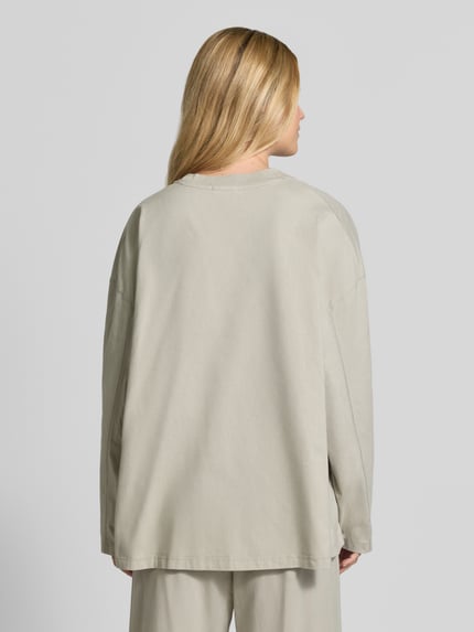 Vrouwenmodel draagt Relaxed Fit Langarmshirt uit katoen van American Vintage, beige tint, ronde hals, trendy, ruglengte maat XS/S: 64 cm, Ganzkörperansicht Rückansicht.