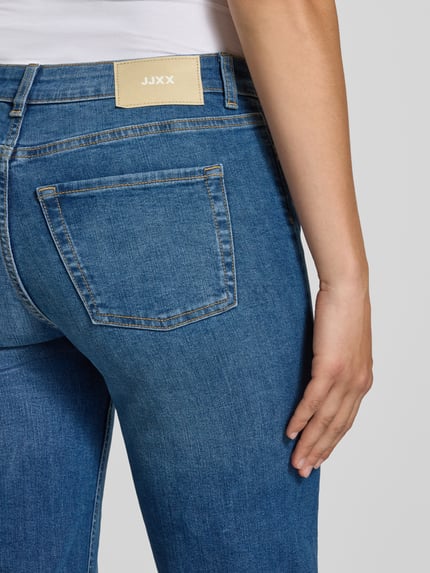 Frauenmodel trägt Flared Jeans mit Knopfverschluss Modell 'ROME' von JJXX, blauer Baumwoll-Mix mit Stretch, Nahaufnahme Rückansicht, 5-Pocket-Design.