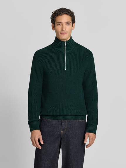 Männermodel trägt Slim Fit Strickpullover aus reiner Baumwolle mit Troyer-Kragen von MCNEAL, grün, gerippte Struktur, Ganzkörperansicht von vorne.