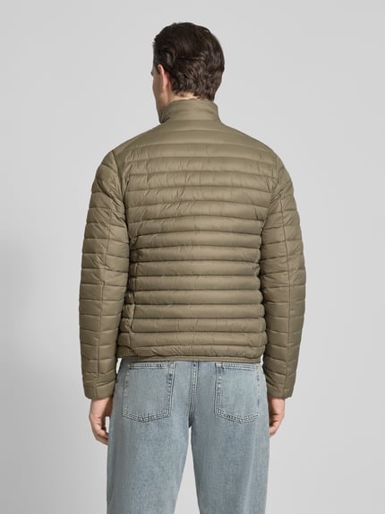 Männermodel trägt olivgrüne Steppjacke mit Zweiwegereißverschluss Modell 'Alexander' von SAVE THE DUCK, Ganzkörperansicht Rückansicht, Stepp-Optik, Regular Fit, gefütterter Stehkragen, glatte Textur, Eingrifftaschen mit Reißverschluss, Maße laut Kontext.
